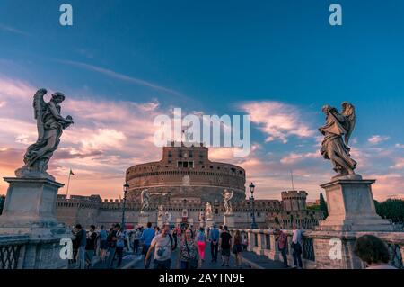 ROM, Italien - 21. September 2013: Blick auf das berühmte Wahrzeichen der römischen Burg Saint Angelo und Brücke mit Touristen bei Sonnenuntergang Stockfoto
