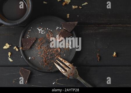 Schwarze leere Platte mit Kuchenresten von oben auf Holzhintergrund Stockfoto