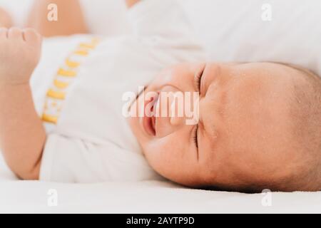 Nahaufnahme des weinenden Neugeborenen zu Hause im Bett. Hungriger Säuglingsjunge schreit nach Milch Stockfoto