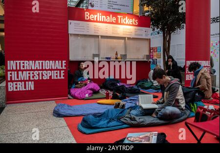 Berlin, Deutschland. Februar 2020. Filmliebhaber sitzen auf Schlafmatten und Schlafsäcken im Potsdamer Platz Arkaden vor einer noch geschlossenen Kiste mit der Aufschrift "Berlinale Tickets" und warten auf den Beginn des Ticketverkaufs für das Internationale Filmfestival "Berlinale". Credit: Paul Zinken / dpa / Alamy Live News Stockfoto