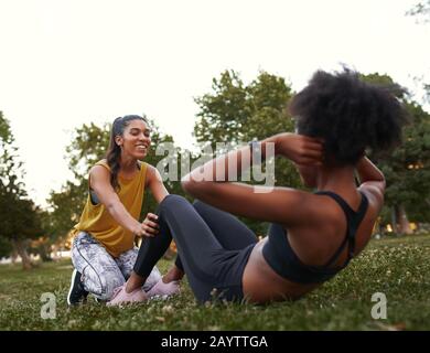 Junge sportliche fit aktive Frauenfreunde sitzen auf grünem Gras im Park Stockfoto