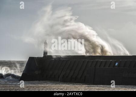 Sturm Dennis bringt hohe Winde und sendet Wellen, die über den Leuchtturm bei Porthcawl in Südwales brechen (16. Februar 2020) Stockfoto