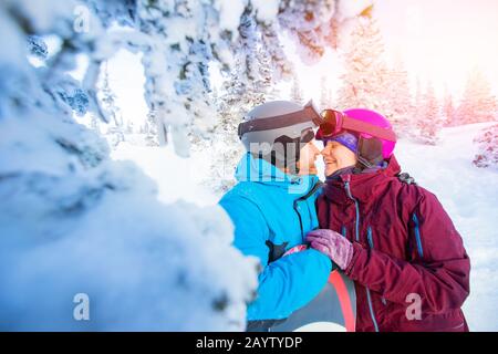 Liebevolles Paar in Anzügen umarmen und küssen sich im Hintergrund des Winterwaldes. Familienurlaub Stockfoto