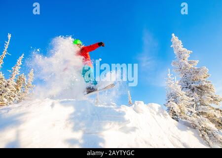 Snowboarder springen mit tiefblauem Himmel im Hintergrund durch die Luft, Freeride Winterwald Stockfoto