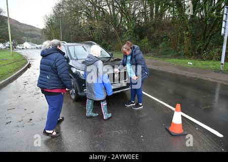 NUMMERNSCHILD PIXELIERT VON PA PICTURE DESK Rachel Cox (ganz rechts) steht neben ihrem neu gekauften Auto, das durch Flutwasser beschädigt wurde, nachdem sie es ein Viertel Meile von ihrem Haus in Nantgarw in Südwales gefunden hat, Wo die Bewohner in ihre Häuser zurückkehren, um die Schäden nach dem Sturm Dennis zu untersuchen und zu beheben. Stockfoto