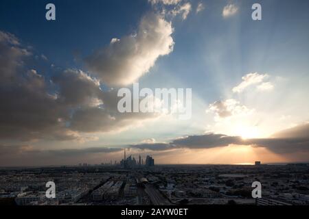 In diesem Weitwinkelschuss von Dubai, in dem die Wolkenkratzer der Innenstadt und die Scheich Zayed Road in der Ferne sichtbar sind, untergeht die Sonne Wolken. Stockfoto