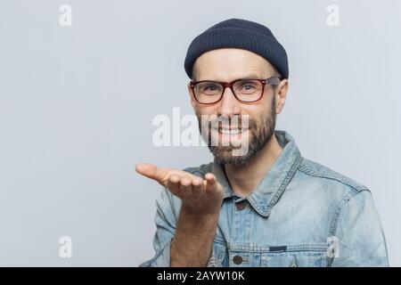 Froh, bärtigen Mann in modischen Brillen drückt seine Liebe, zeigt, kiss, hat freundliche Ausdruck, über grauer Hintergrund isoliert. Blue eyed mittleren Alters Stockfoto