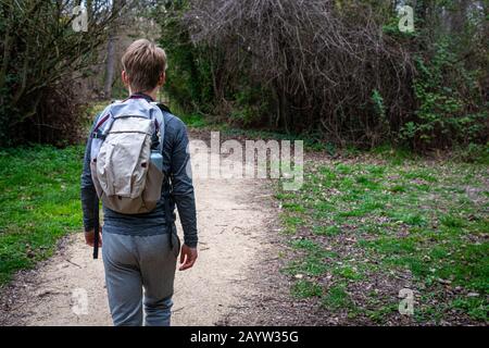 Junger Wanderer, der Weg im Wald folgt.Rückansicht.mit Rucksack & Wasserflasche. Stockfoto