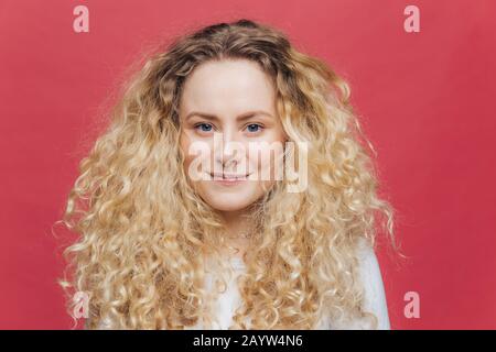 Isolierter Schuss von jungen adligen Weibchen mit lockigen Haaren und blauen Augen, hat guten Ausdruck, wirkt ansprechend und ist nach gut w in hohem Geist Stockfoto