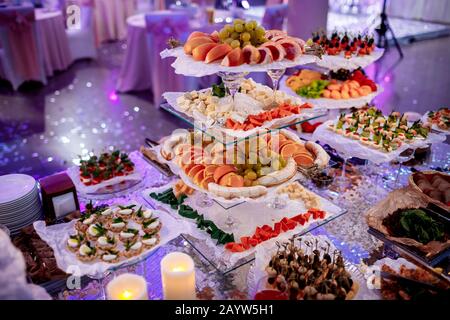 Großartige, attraktive Vorhänge mit Gemüse, Käse, Obst, Beeren, Salami, Fisch und Meeresfrüchten, Fleisch und Dekoration auf der Hochzeit. Stockfoto