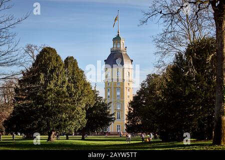 Karlsruhe, 15. Februar 2020: Karlsruher Palast mit erhöhter Flagge umgeben von Bäumen und blauem Himmel. Blick vom Schlossgarten an einem sonnigen Tag Stockfoto