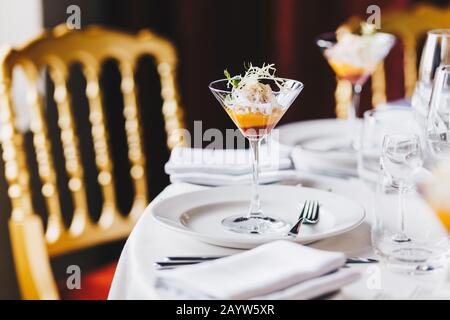 Serviert wird ein Tisch mit Cocktail, weißem Tischtuch, Besteck und Cocktail für die Hochzeit. Bankett im Luxus-Café oder Restaurant. Keine Personen auf dem Foto. Koz Stockfoto