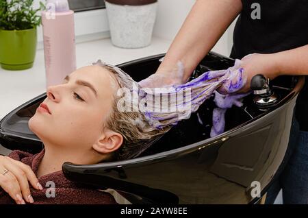 Haarstylisten, die nach dem Färben violettes Shampoo färben. Stockfoto