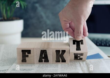 Fake oder FAKT, deutsch in der Tat, auf Holzblöcken auf Zeitung, echte Nachrichten oder gefälschtes Nachrichtenkonzept Stockfoto