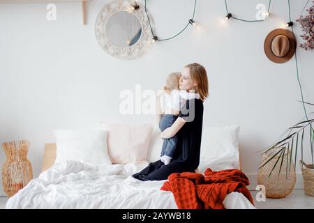 Glückliche Familie, junge Frau Mutter umarmt und beruhigt Tochter des Kindes nach Magenkolik Stockfoto