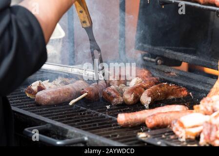 Rauchende Wurst und Fleisch auf einem Holzkohlengrill. Stockfoto