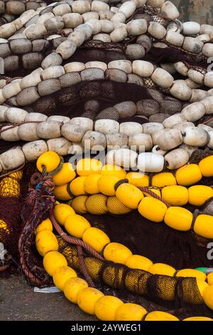 Fischernetthaufen mit gelben und weißen Bojen auf der Straße eines Hafens. Essaouira, Marokko. Stockfoto