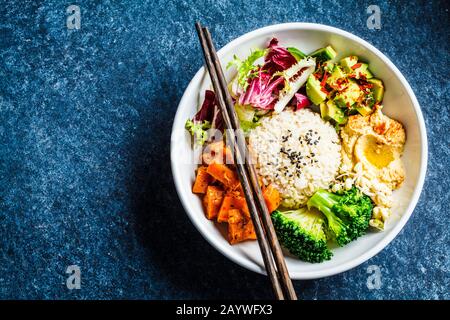 Buddha-Schüssel. Veganer Reis- und Gemüsesalat. Makrobiotischer Satz mit Reis, Hummus, Avocado, Brokkoli und Süßkartoffel. Stockfoto