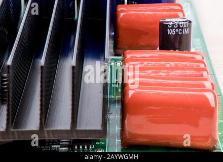 Eine Reihe von Kondensatoren und ein schwarzer Kühler zur Kühlung auf einer elektronischen Leiterplatte. Nahaufnahme. Stockfoto