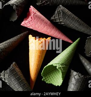Drei leere bunte grüne, pinke und gelbe Eiskegel unter den grauen in einer Nahansicht im quadratischen Format Stockfoto