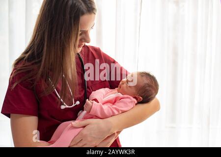 Kinderarzt, der ein schönes neugeborenes Mädchen hält Stockfoto