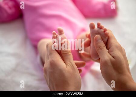 Mutter oder Arzt massieren den Fuß des kleinen Babys Stockfoto