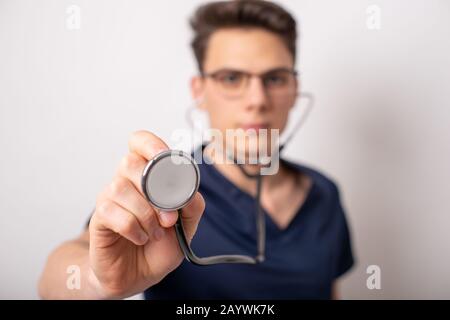 Hübscher Junge Sanitäter halten ein Stethoskop, isoliert auf weiß Stockfoto