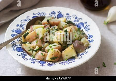 Traditionelle kalte Kartoffelsalat mit Zwiebeln und Kräutern auf einem Leinen Tischdecke Hintergrund. Im rustikalen Stil. Stockfoto