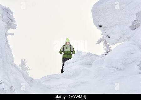 Man Reisende in den Winterbergen unter den schneebedeckten Klippen während eines blizzards Stockfoto