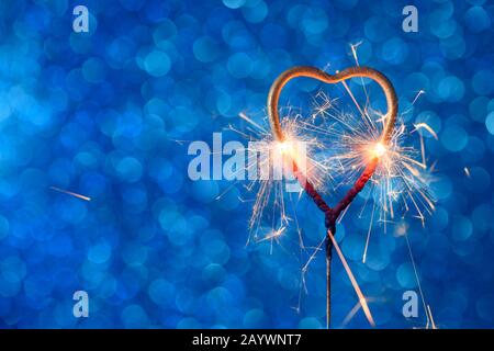 Liebe Hochzeit Valentinstag Party bengalen Feuer. Brennendes funkelndes Herz auf blauem Bokeh-Hintergrund. Stockfoto