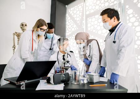 Multiracial junge Medizin Apotheken Studenten oder Forscher mit männlichen Vorgesetzten in Labormänteln und Masken. Der Doktor-Professor hat eine Praxis mit Studenten Stockfoto