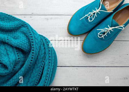 Ein Paar Frauen mit niedrigem Schuh und blauem Pullover auf hellem Holzhintergrund. Flaches Lay, moderne Trends der Modebekleidung. Draufsicht. Lässiges Style-Konzept Stockfoto