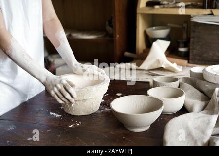 Weibliche Hände halten eine Schüssel für das Gießen von Ton-Produkte. Stockfoto