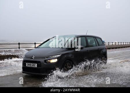 Autos, die auf der überfluteten Promenade in New Brighton Merseyside während des kürzlichen Sturms Ciara fahren. Stockfoto