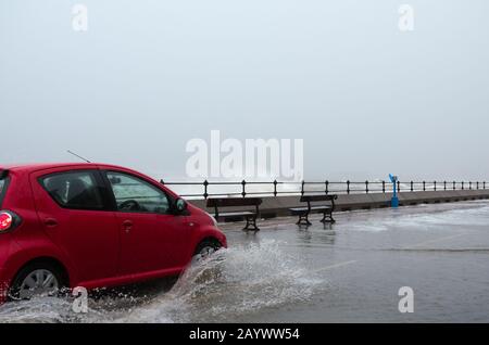 Autos, die auf der überfluteten Promenade in New Brighton Merseyside während des kürzlichen Sturms Ciara fahren. Stockfoto