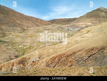 Blick über das Tal von Spiti und das Dorf Chicham in der Entfernung, die vom hohen Himalaya unter hellem Himmel in der Nähe von Chicham, Himachal Pradesh, Indien isoliert ist. Stockfoto