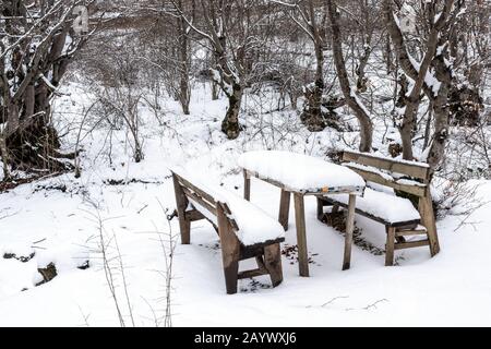 Mit Schnee bedeckter Tisch und Bank im Garten Stockfoto