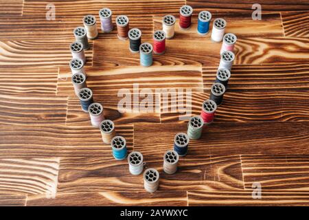 Viele seitliche aline-faden-Spulen in Herzform auf Holzhintergrund Stockfoto