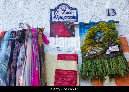 Örtlich herzufügendes Kunsthandwerk, das im Februar vor dem Laden in El Zoco Alpujarreno in Pampaneira, Andalucia, Spanien, hängt Stockfoto