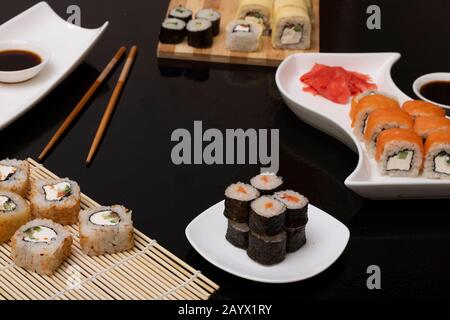 Philadelphia rollen Sushi mit Lachs, Garnelen, Avocado, Frischkäse. Sushi-Menü. Japanische Küche auf schwarzem Hintergrund Stockfoto