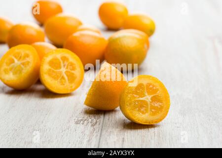 Haufen von Kumquat-Früchten, chinesische Mandarinen, auf Holztisch. Stockfoto