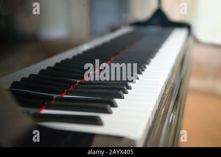 Seitenansicht des Klaviers mit Tasten, die im Licht verloren gehen. Seitenansicht der Klaviertasten mit geringer Schärfentiefe. Klaviertasten monochrom. Tastatur, die auf den erweitert wird Stockfoto