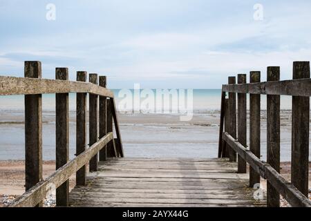 Schuss aus Sicht auf das stehen auf einer Holzbrücke, Blick auf den Horizont am Strand bei Ebbe. Stockfoto