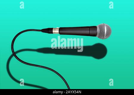 Kabelgebundenes schwarzes und graues Singer-Mikrofon auf grünem Hintergrund Stockfoto