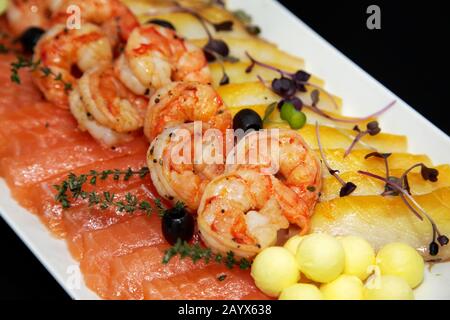 Verschiedene Garnelen, Forellen und ölige Fische mit Ölkugeln und schwarzen Oliven Stockfoto