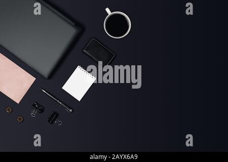 Schwarzer Schreibtisch. Arbeitsbereich auf schwarzem Tisch mit Arbeitsmaterial. Stockfoto