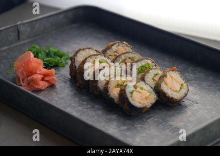 Sushi-Mahlzeit mit Ingwer und Wasabi auf einem Metallplättchen. Sushi-Set - Verschiedene Arten von Maki Sushi und Nigiri. Speisekarte mit Fischgerichten. Stockfoto