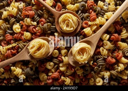 Drei Holzlöffel auf einem Bett aus getrockneter Pasta Stockfoto