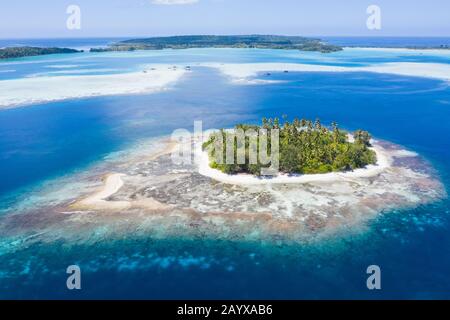 Eine abgelegene Insel befindet sich inmitten der heiteren Seescape in Raja Ampat, Indonesien. Diese tropische Region ist ein großer Teil des Korallendreiecks. Stockfoto