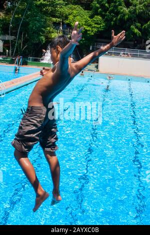 Der Junge taucht in der Luft in den Swimmingpool ein Stockfoto